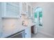 Bright wet bar with white cabinetry, quartz countertops, a stainless-steel cooler, and natural light from a window at 147 Bay Point Ne Dr, St Petersburg, FL 33704