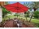 A red umbrella shades a seating area in the backyard overlooking the pond at 1528 Riverdale Dr, Oldsmar, FL 34677