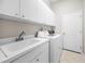 Clean laundry room with white cabinets, washer, dryer, and a utility sink at 1528 Riverdale Dr, Oldsmar, FL 34677