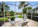 The screened patio features a glass-topped table with four chairs overlooking the pond at 1528 Riverdale Dr, Oldsmar, FL 34677