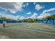View of the community's tennis courts surrounded by lush greenery with blue privacy screens at 1528 Riverdale Dr, Oldsmar, FL 34677
