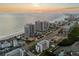 Expansive aerial view shows beachfront condos with pools, tennis courts, and stunning sunset backdrop at 1581 Gulf Blvd # 403N, Clearwater Beach, FL 33767