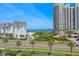 Scenic daytime view of the property's exterior with palm trees, lush landscaping, and glimpses of the ocean at 1581 Gulf Blvd # 403N, Clearwater Beach, FL 33767
