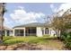 Back exterior of home with screened patio, lush green lawn and landscaping at 1852 Longview Ln, Tarpon Springs, FL 34689