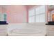 Bright bathroom with large tub under a window and striped wallpaper at 1852 Longview Ln, Tarpon Springs, FL 34689