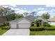 A charming home with a manicured lawn, a two-car garage, and a welcoming red front door at 1852 Longview Ln, Tarpon Springs, FL 34689