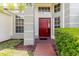 Charming front entrance with a red door, a brick walkway, and manicured landscaping at 1852 Longview Ln, Tarpon Springs, FL 34689