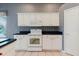Charming kitchen featuring white cabinetry, black countertops, and modern appliances at 1852 Longview Ln, Tarpon Springs, FL 34689