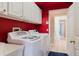 Red laundry room with white cabinets and a washer and dryer at 1852 Longview Ln, Tarpon Springs, FL 34689