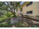 Exterior view of the condo showcasing lush landscaping and a large tree providing shade at 2003 Greenbriar Blvd # 1, Clearwater, FL 33763