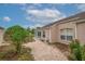 Exterior view of the home with a brick path leading to the enclosed porch and manicured landscaping at 241 Royal Palm Way, Spring Hill, FL 34608