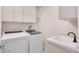 Laundry room with white washer and dryer, built-in cabinets, and a utility sink at 241 Royal Palm Way, Spring Hill, FL 34608
