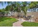 Landscaped backyard featuring a grass lawn, brick border, hammock, and fire pit with seating at 30317 Rattana Ct, Wesley Chapel, FL 33545