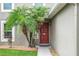 Inviting entryway with a red front door framed by lush tropical palms and attractive landscaping at 30317 Rattana Ct, Wesley Chapel, FL 33545