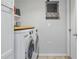 Clean laundry room with a side-by-side washer and dryer, convenient shelving, and tile floor at 30317 Rattana Ct, Wesley Chapel, FL 33545