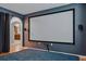 Media room featuring a large projection screen, hardwood floors, and adjacent kitchen view at 30317 Rattana Ct, Wesley Chapel, FL 33545
