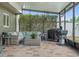 Screened patio featuring brick floors and comfortable seating, along with a grill for outdoor cooking at 30317 Rattana Ct, Wesley Chapel, FL 33545