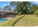 Beautifully landscaped backyard featuring a screened pool area and manicured lawn at 3133 Harvest Moon Dr, Palm Harbor, FL 34683