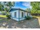 Corner view of a single-story home featuring white siding, blue trim, and a metal roof, surrounded by mature trees at 3147 Sydney Dover Rd, Dover, FL 33527
