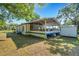 View of a single-story home with a large screened-in porch, storage shed, and mature trees providing shade at 3147 Sydney Dover Rd, Dover, FL 33527