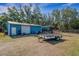Blue outbuilding with roll up door, standard door, and trailer parked on the property at 3147 Sydney Dover Rd, Dover, FL 33527