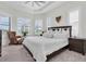 Bright bedroom featuring a large bed, wicker chair, plantation shutters, and neutral tones at 3167 Forsythia Dr, Odessa, FL 33556