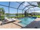 Screened-in pool features brick surround, waterfall feature, and tranquil lake views at 3167 Forsythia Dr, Odessa, FL 33556