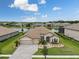 Expansive aerial view of a tile roofed home, a tranquil pond, and well-maintained lawns at 33219 Kateland Dr, Wesley Chapel, FL 33545