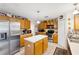 Functional kitchen featuring oak cabinets, tile flooring, and a stainless steel refrigerator at 3411 Landover Blvd, Spring Hill, FL 34609