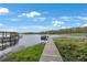 Scenic view of a wooden dock extending into the lake with lush vegetation and a charming boat house at 4783 School Rd, Land O Lakes, FL 34638