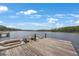 View of the dock and pontoon boat on the lake with a clear blue sky and some clouds at 4783 School Rd, Land O Lakes, FL 34638