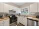 Well lit kitchen features stainless steel appliances, white cabinets, and a window at 4783 School Rd, Land O Lakes, FL 34638