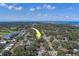 Aerial view of a quiet neighborhood, mature trees, and clear view of the ocean. Property of interest denoted with yellow arrow at 501 Poinsettia Rd, Belleair, FL 33756