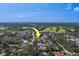 An aerial view of a golf community with mature trees and beautiful landscaping. The property is denoted with a yellow arrow at 501 Poinsettia Rd, Belleair, FL 33756