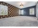 Empty bedroom with black and gold floral accent wall, chandelier, and carpet at 6227 Golden Nettle Dr, Apollo Beach, FL 33572