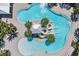 Aerial view of a resort-style pool with waterslides and lounge chairs surrounded by lush landscaping and clear blue water at 6227 Golden Nettle Dr, Apollo Beach, FL 33572