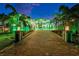 Elegant home featuring a long driveway, manicured gardens, lush palm trees, and inviting outdoor lighting at 6526 Surfside Blvd, Apollo Beach, FL 33572