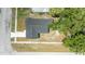 An aerial view of the home featuring a dark roof, a walkway, and a well-maintained yard, surrounded by mature trees at 6816 S Hesperides St, Tampa, FL 33616
