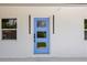 Close-up of the home's modern blue front door flanked by windows and white walls at 6816 S Hesperides St, Tampa, FL 33616