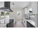 Modern kitchen features black range hood, white cabinetry, marble countertops, and stainless steel appliances at 6816 S Hesperides St, Tampa, FL 33616