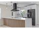 Modern kitchen featuring white cabinetry, a black range hood, and a large center island with seating at 6816 S Hesperides St, Tampa, FL 33616