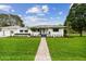 Charming single-story home featuring a well-manicured front lawn and walkway leading to the entrance at 7224 Park S St, St Pete Beach, FL 33707