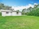 Expansive backyard featuring lush green grass, mature trees, and a covered patio, perfect for outdoor entertaining at 8329 Gulf Way, Hudson, FL 34667