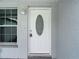 Close-up of white front door with oval window and sidelight near a window at 8329 Gulf Way, Hudson, FL 34667