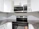 Modern kitchen features white cabinets, granite countertops, herringbone backsplash, and stainless steel appliances at 8329 Gulf Way, Hudson, FL 34667