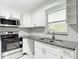 Kitchen featuring stainless steel appliances, granite countertops, white cabinets, and herringbone backsplash at 8329 Gulf Way, Hudson, FL 34667