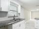 Kitchen featuring stainless steel sink, granite countertops, white cabinetry, and bright lighting at 8329 Gulf Way, Hudson, FL 34667