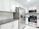 Modern kitchen featuring granite countertops, white cabinetry, stainless steel appliances, and tiled backsplash at 8329 Gulf Way, Hudson, FL 34667