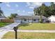 Inviting home exterior with a well-maintained lawn, long driveway, and classic architectural details under a blue sky at 9053 Hickory Cir, Tampa, FL 33615