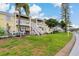 Exterior view of yellow townhomes with white railings, stairs and lush green lawns at 101 Pompano Se Dr # C, St Petersburg, FL 33705
